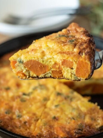 Serving a slice of sweet potato and sage frittata with chunks of sweet potato and sage showed inside