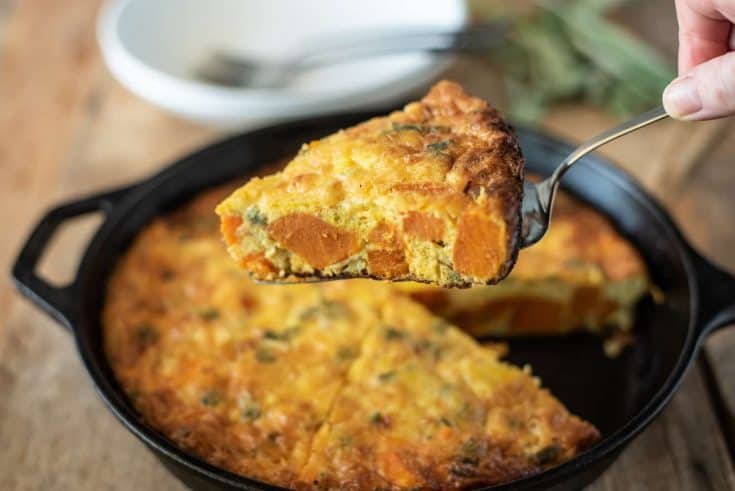 Serving a slice of sweet potato and sage frittata with chunks of sweet potato and sage showed inside