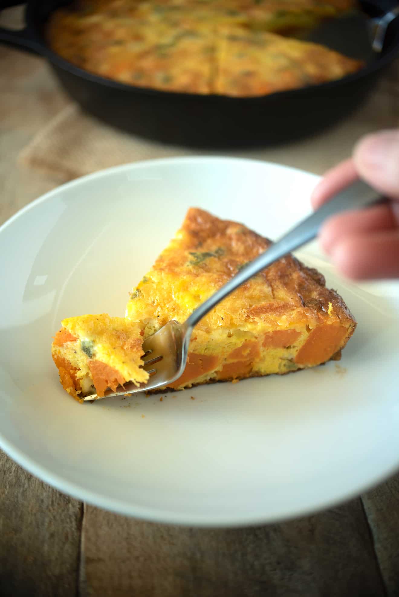 Using a fork to get a bite of sweet potato and sage frittata