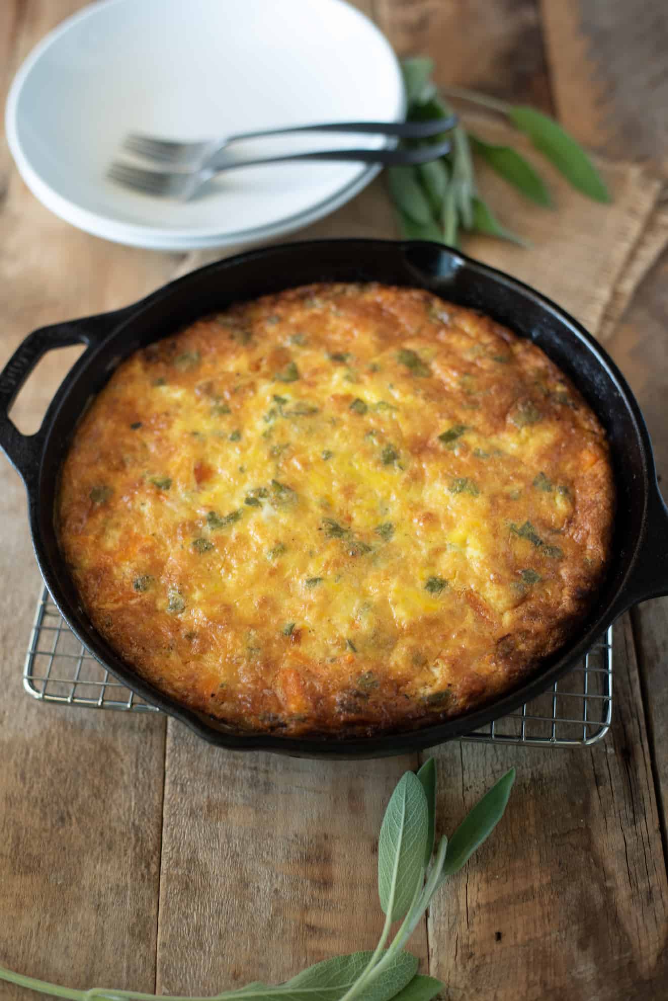 Sweet potato and sage frittata in a cast iron skillet with fresh sage