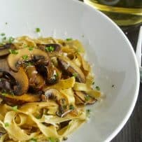 A closeup of the meaty mushrooms on top of fresh tagliatelle