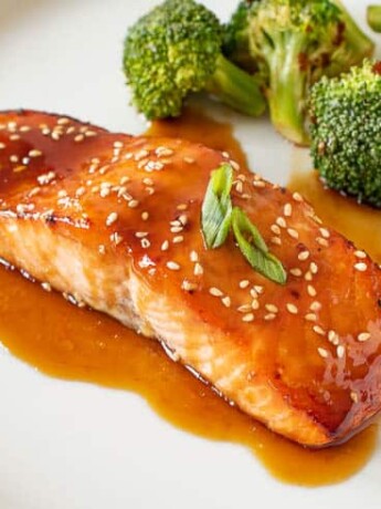 Teriyaki Glazed Salmon on a white plate with green onion and broccoli