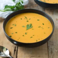 Smooth butternut squash soup served in a bowl garnished with green parsley