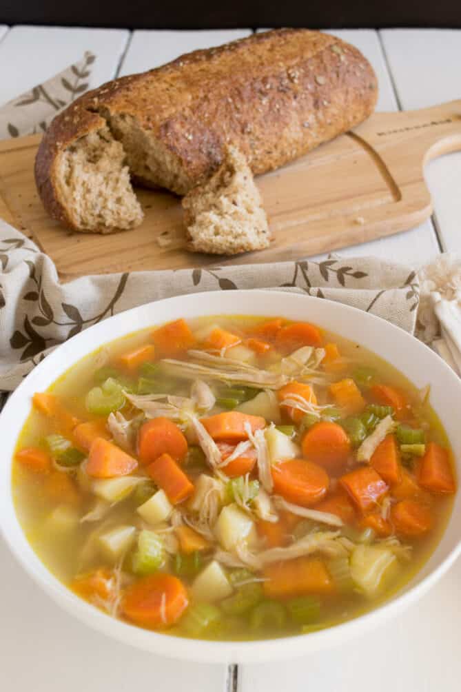 A bowl of chicken soup with crusty bread