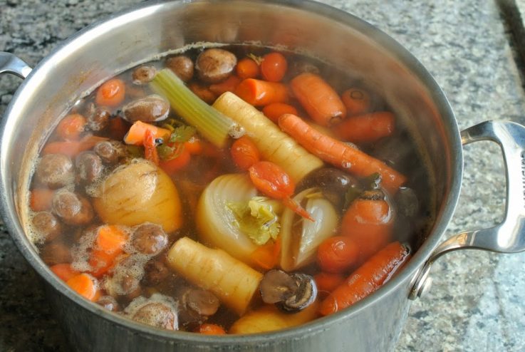 A large pan of vegetables bubbling to make the vegetable stock