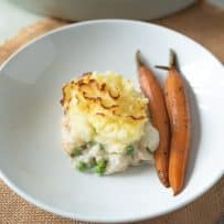 A serving of fish pie on a white plate with carrots