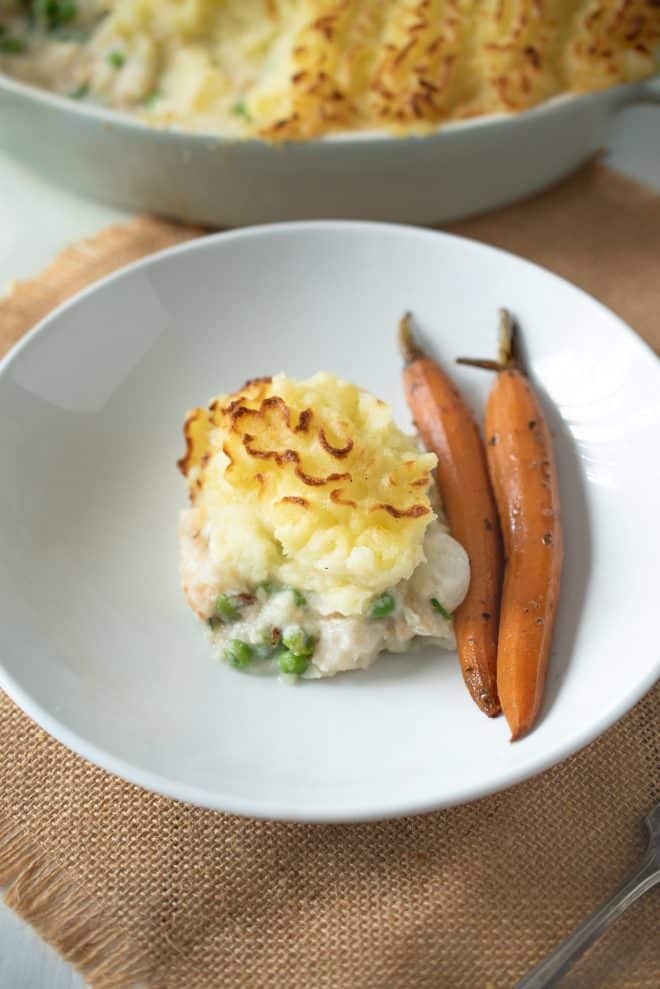 A serving of fish pie on a white plate with carrots