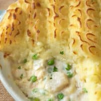 Creamy sauce with fish and peas topped with decorative mashed potato