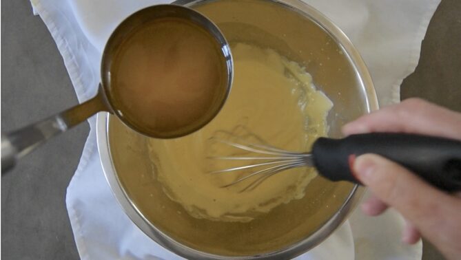 Adding melted clarified butter to whisked egg yolks