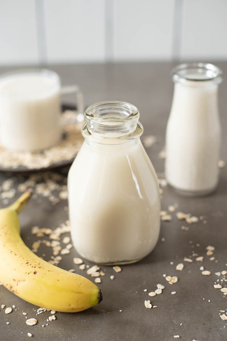 2 milk bottles filled with oat milk with a banana