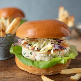 A side view of a tilapia burger on a bun with French fries