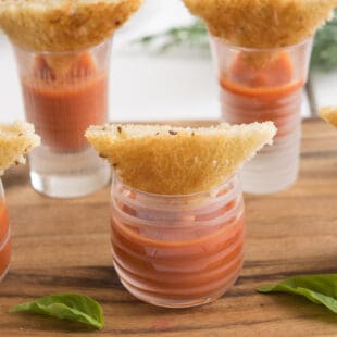 Crustless mini grilled cheese triangles served party style with tomato soup shots