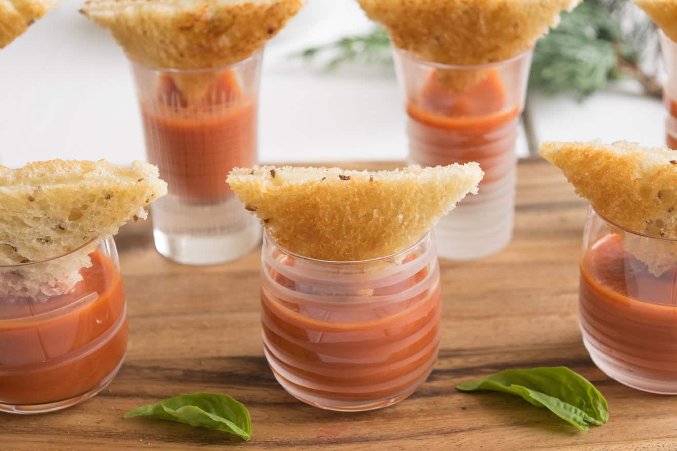 Crustless mini grilled cheese triangles served party style with tomato soup shots