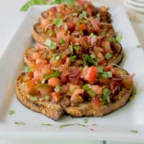 Crispy slices of bread topped with chopped tomato, basil and crispy prosciutto