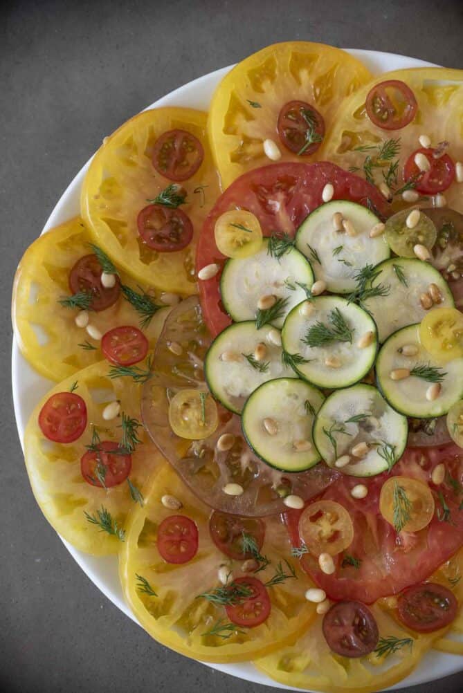 A overhead view of tomato slices and zucchini slices in a pretty display