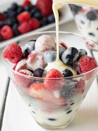 Frozen berries in a glass bowl with vanilla custard