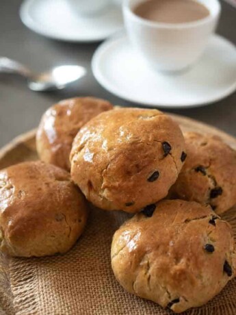 Currant studded teacake buns served with a cup of tea