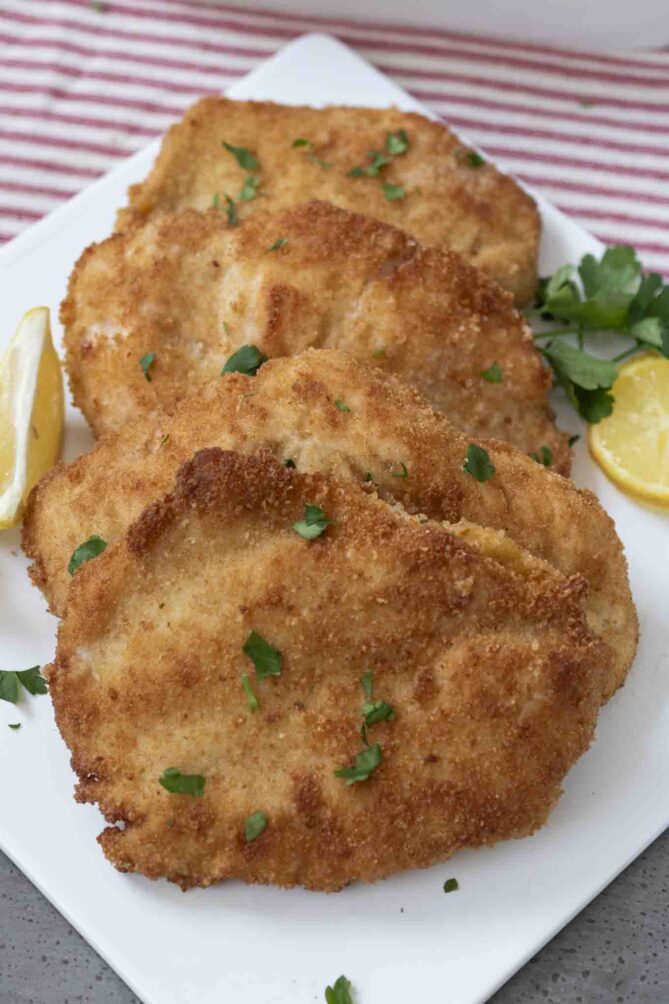 4 chicken cutlets on a white plate