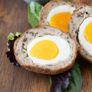 A closeup of the inside of a Scotch egg showing the bright yolk