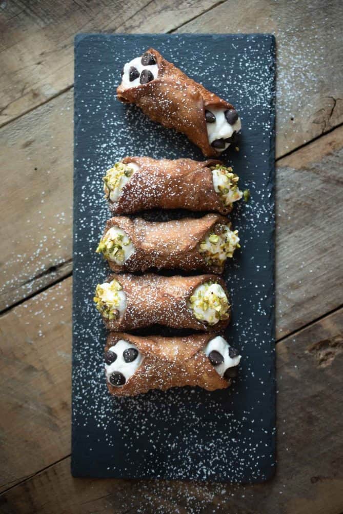 5 cannoli viewed from overhead on a rectangle serving plate