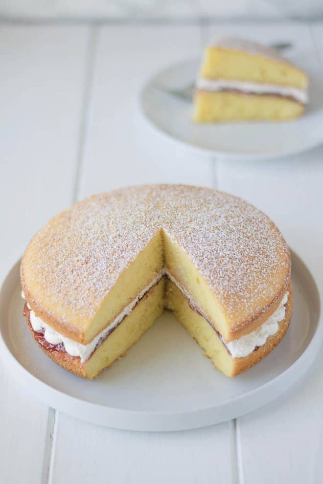 A whole Victoria Sponge Cake with a piece removed