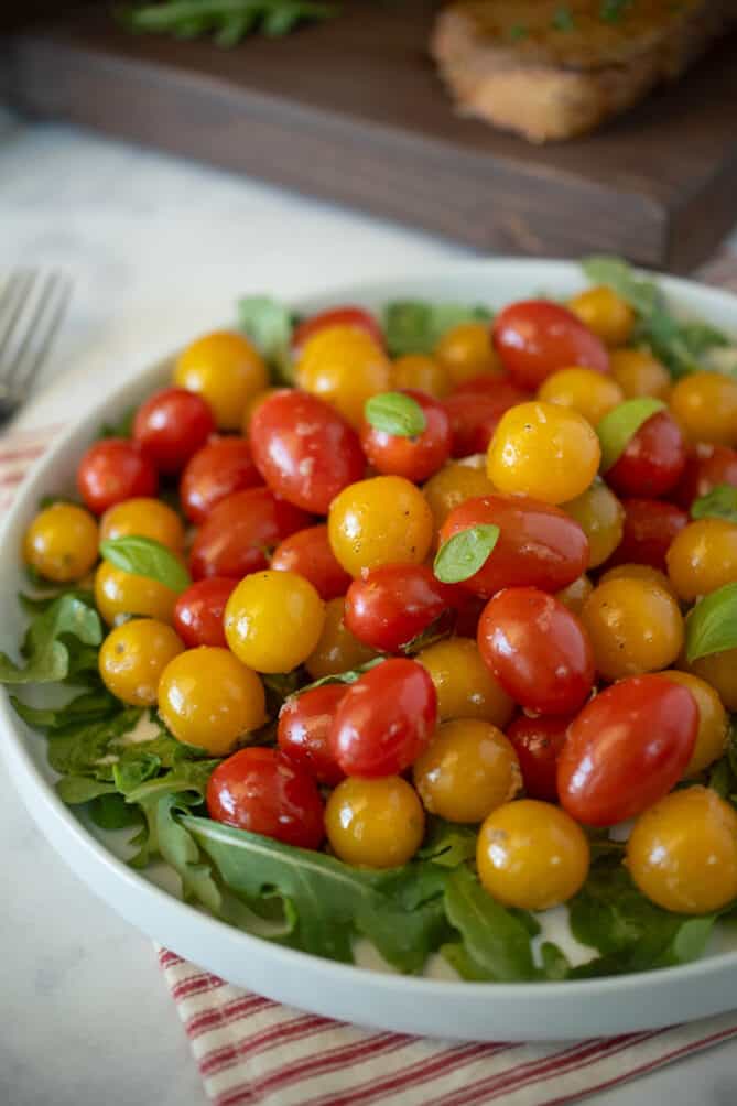 Red and yellow cherry tomatoes on top of arugula