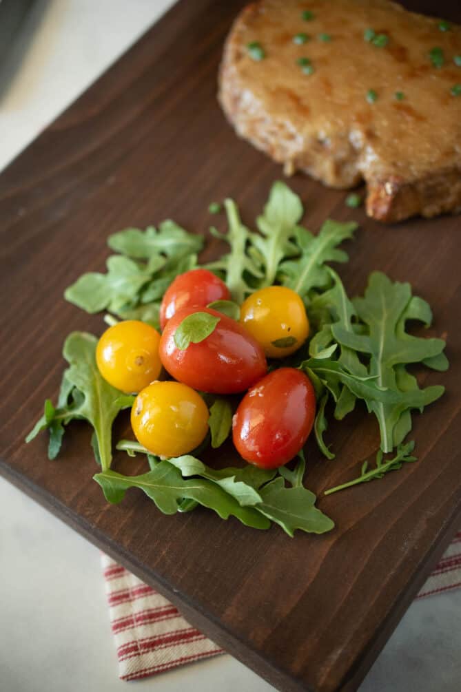 An arugula and cherry tomato salad on a serving board