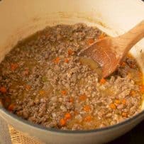 Meaty white Bolognese sauce in a white Dutch oven