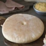 A round loaf of bread called stottie on a board.