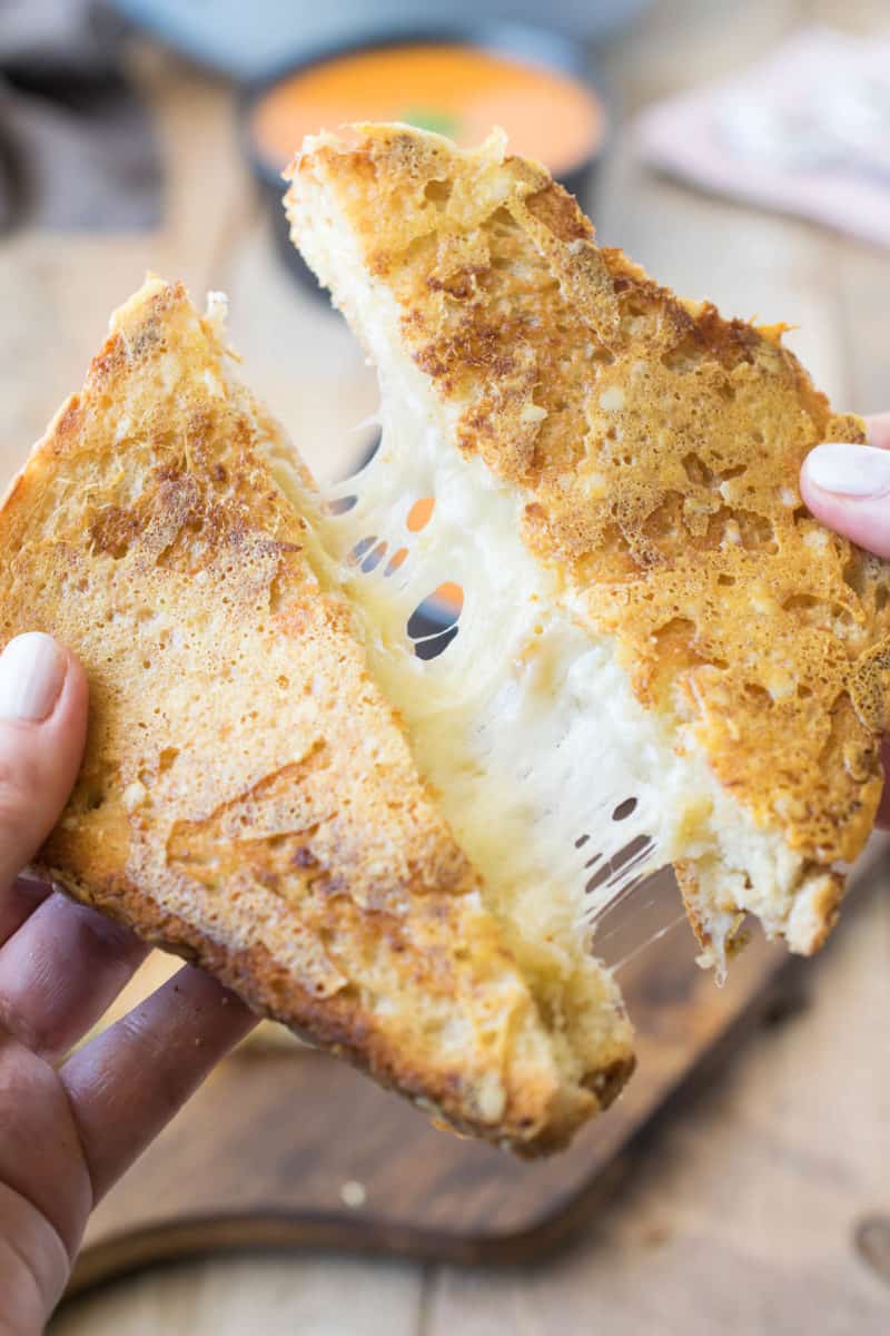 Pulling apart a grilled cheese sandwich to show the stretchy cheese inside