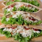 A closeup of tuna salad with coleslaw, grapes and lettuce in pita bread.