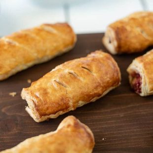 Turkey, stuffing and cranberry sausage rolls lined up on a wooden board