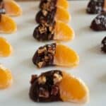 Juicy orange segments, half covered in chocolate, pecans, flaky salt and caramel sauce