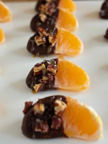Juicy orange segments, half covered in chocolate, pecans, flaky salt and caramel sauce