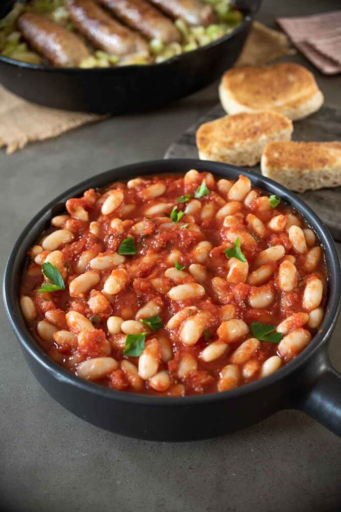 A black bowl full of beans in tomato sauce