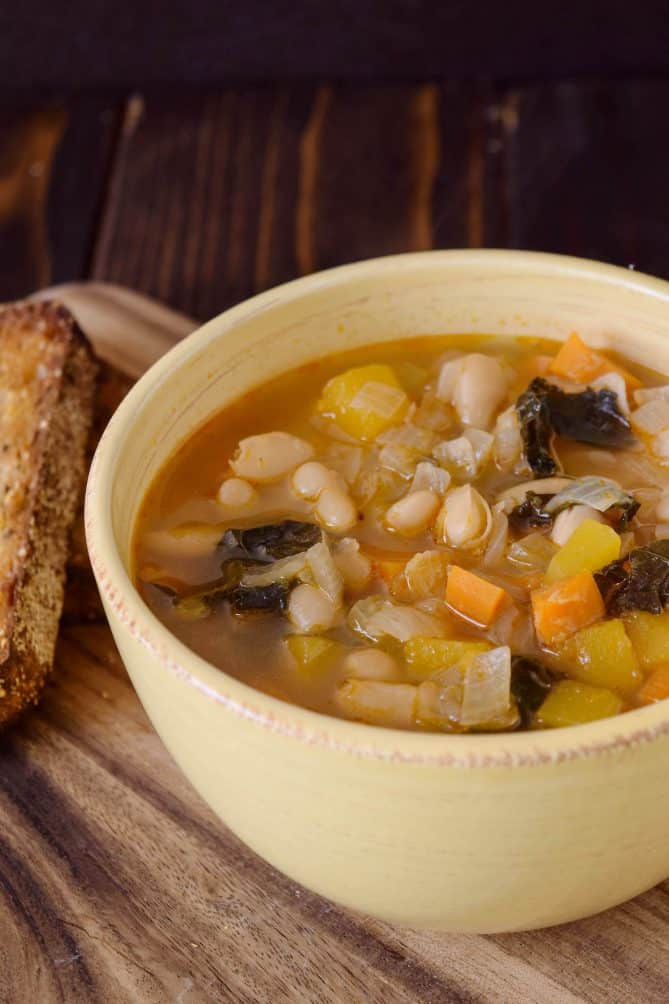A closeup showing the beans carrot butternut squash and carrots in Tuscan kale soup