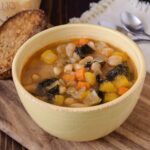 A colorful bean soup in a yellow bowl