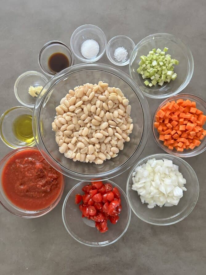 Glass bowls filled with ingredients to make vegetable baked beans