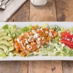 A warm buffalo chicken salad on a white rectangle plate