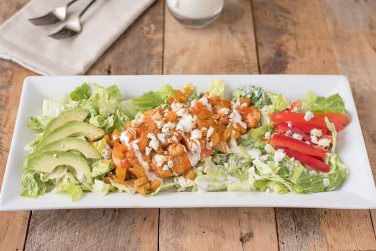 A warm buffalo chicken salad on a white rectangle plate