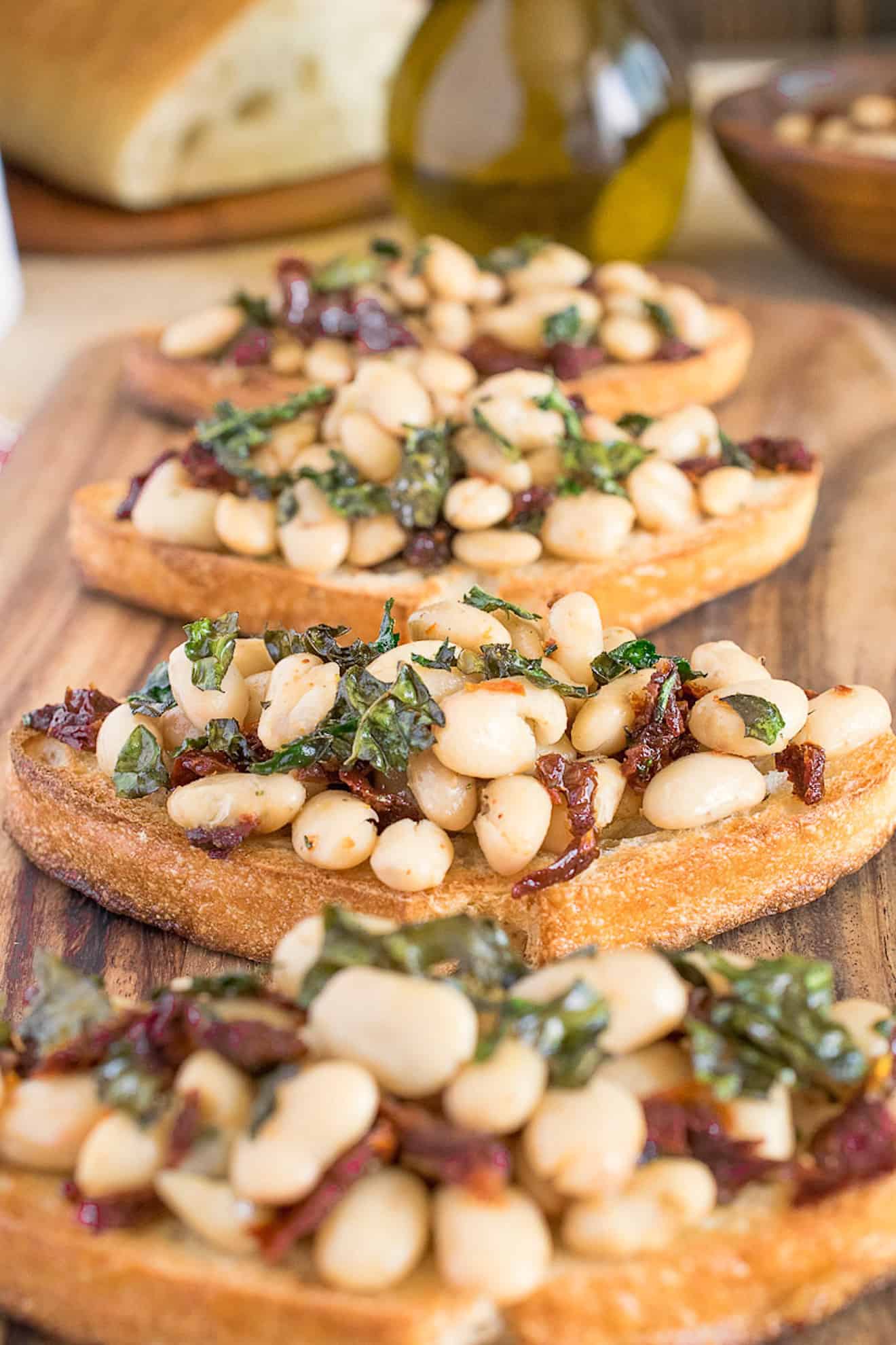 4 Warm Tuscan bean crostini lined up on a board