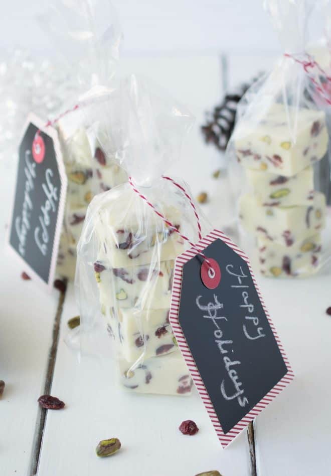White Chocolate Pistachio Cranberry Fudge Squares wrapped in clear bags with Happy Holidays gift tags