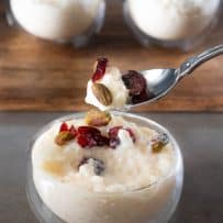 A spoonful of white chocolate rice pudding with dried cranberries and pistachios