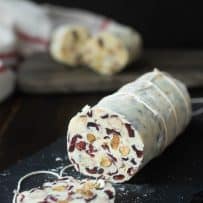 A sliced white chocolate salami with pretty red cranberries inside