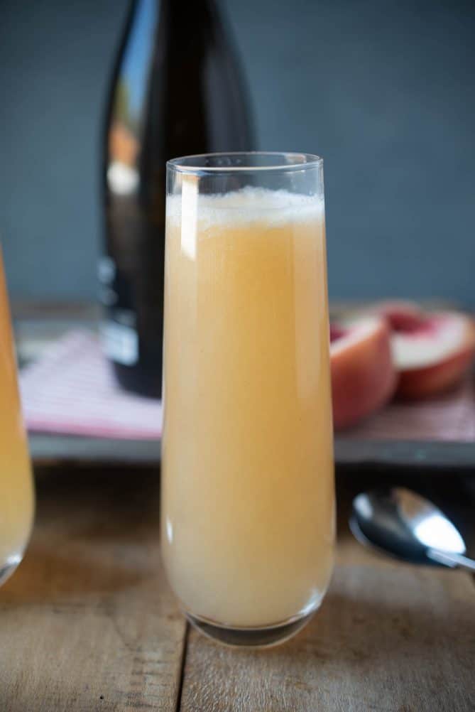 A side view of a tall glass filled with white peach Bellini