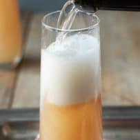 A white peach Bellini pouring Prosecco into the glass