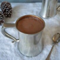 A pewter mug filled with Baileys Belgian hot chocolate on a bed of snow