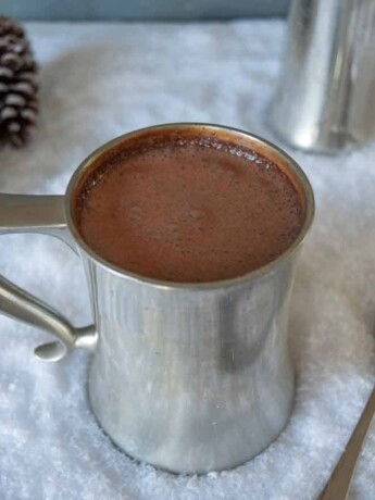A pewter mug filled with Baileys Belgian hot chocolate on a bed of snow