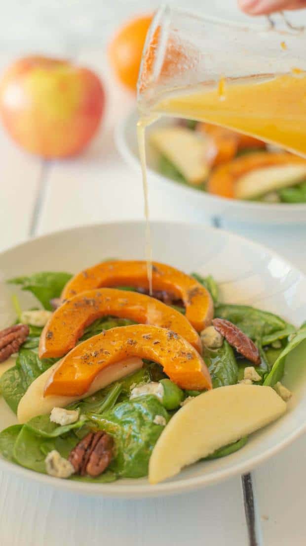 Orange vinaigrette being drizzled onto the salad