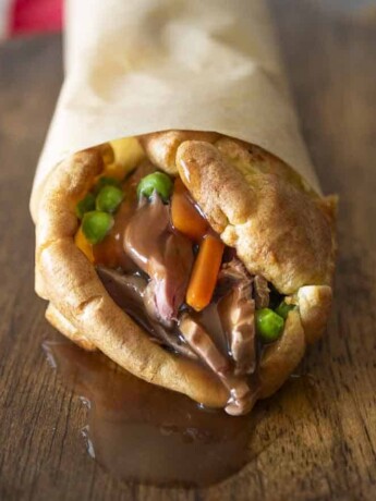 The end view of a Yorkshire burrito with gravy oozing out from roast beef, carrots and peas